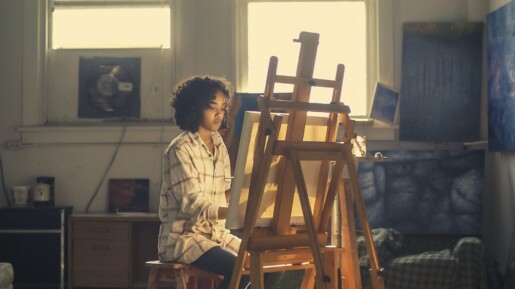 photo of woman painting in brown wooden easel