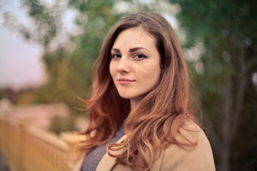 closeup photo of woman with brown coat and gray top